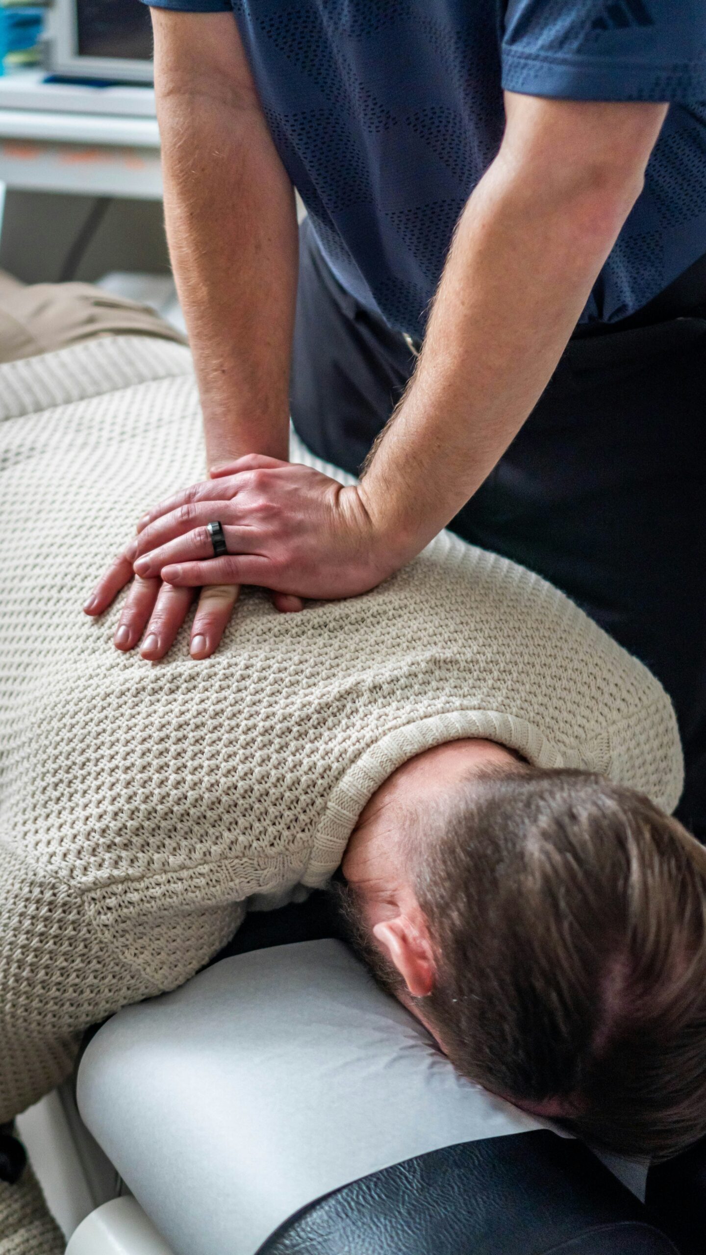 A physiotherapist applying hands-on treatment to a patient’s upper back
