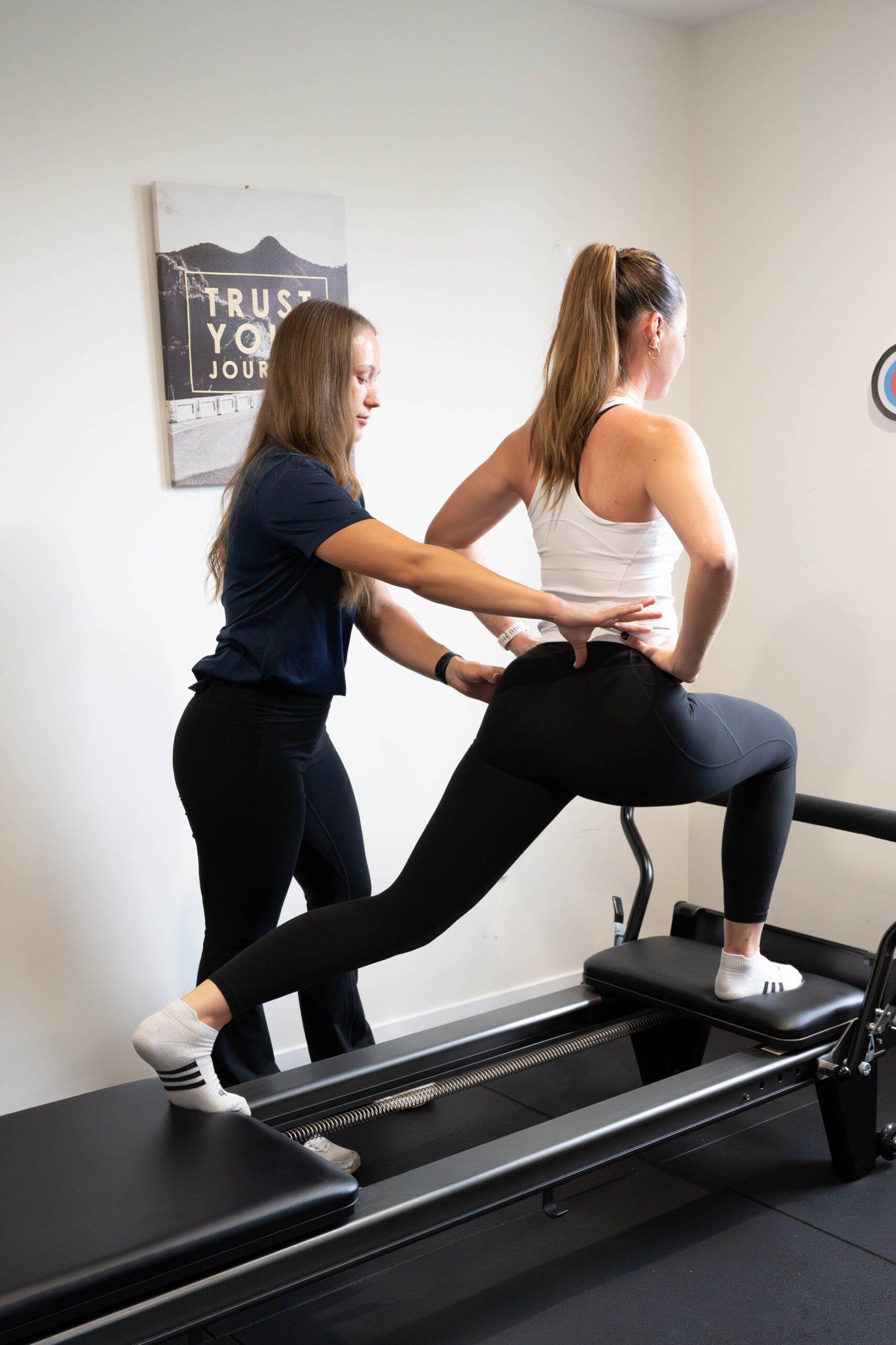 A physiotherapist guiding a patient’s hip position during a lunge on the reformer