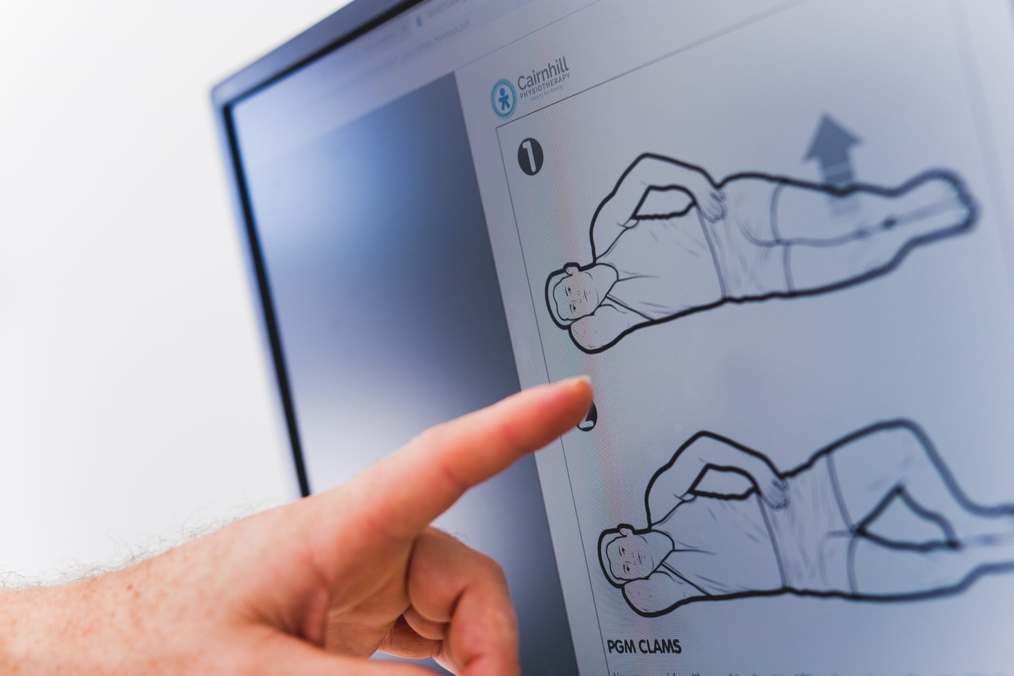 A physiotherapist pointing to a clam exercise on an on-screen home exercise programme