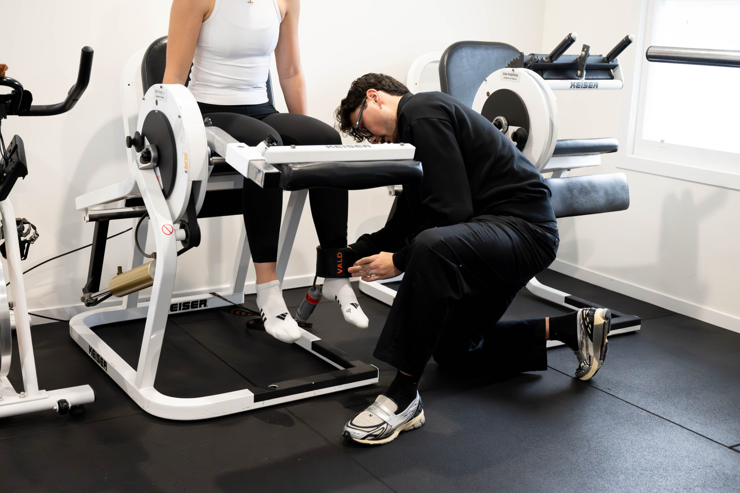 A physiotherapist setting up strength testing on the Keiser machine