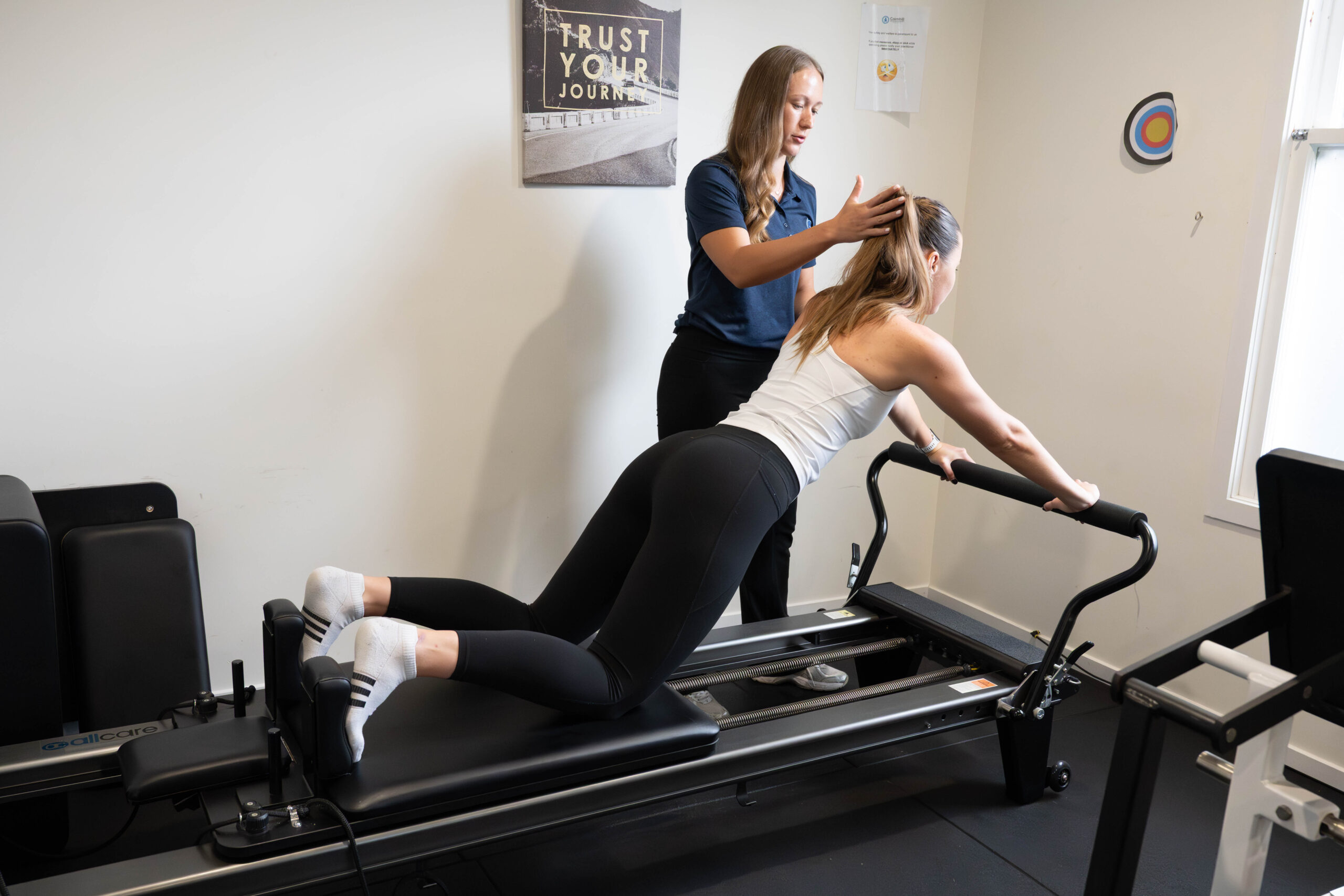 A physiotherapist guiding a client through a reformer Pilates exercise