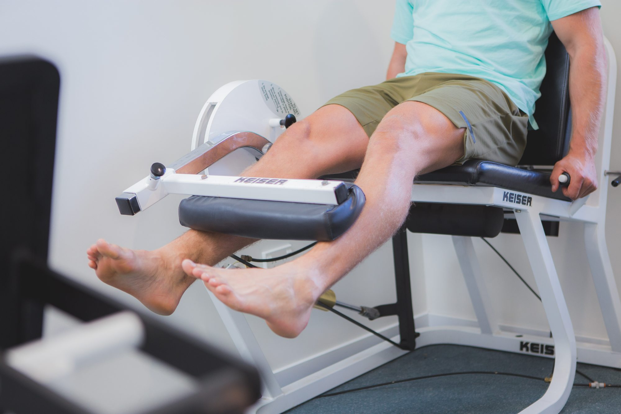 A patient strengthening his knees on a leg extension machine in the rehabilitation gym