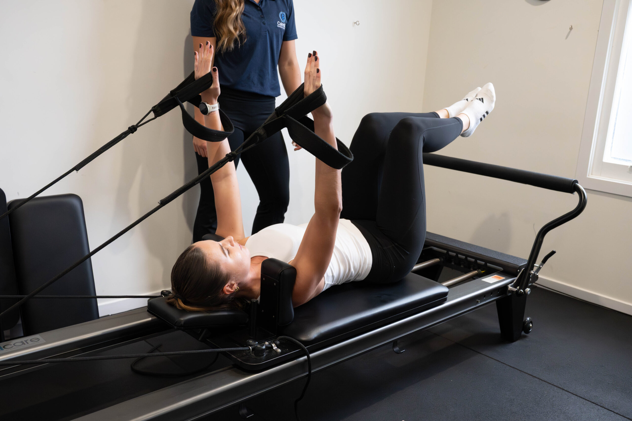 A physiotherapist supporting a client on the reformer