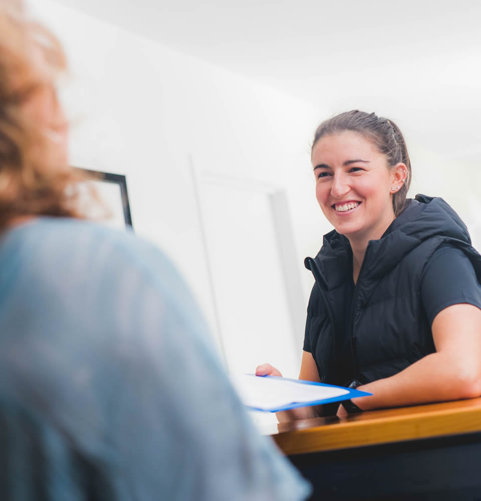 A physiotherapist talking with a patient at reception