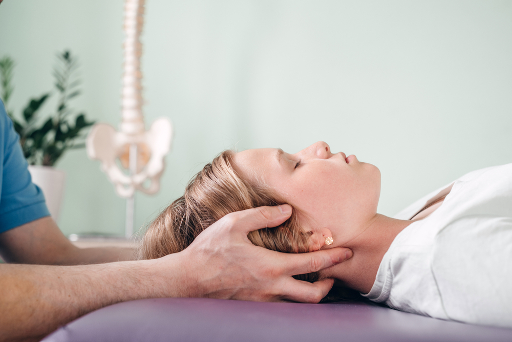 A physiotherapist supporting a patient’s head and neck during treatment