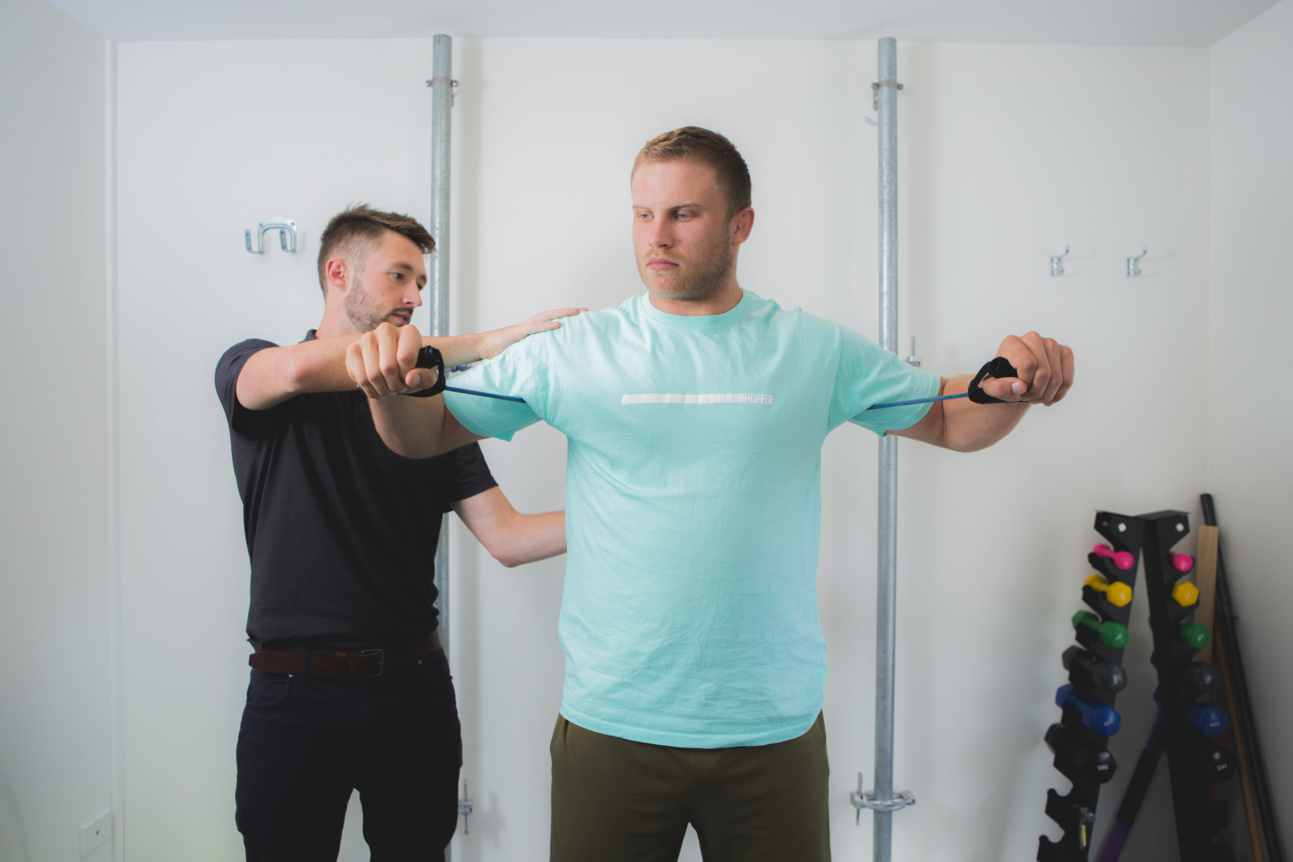 A physiotherapist guiding a patient through a resistance band shoulder exercise